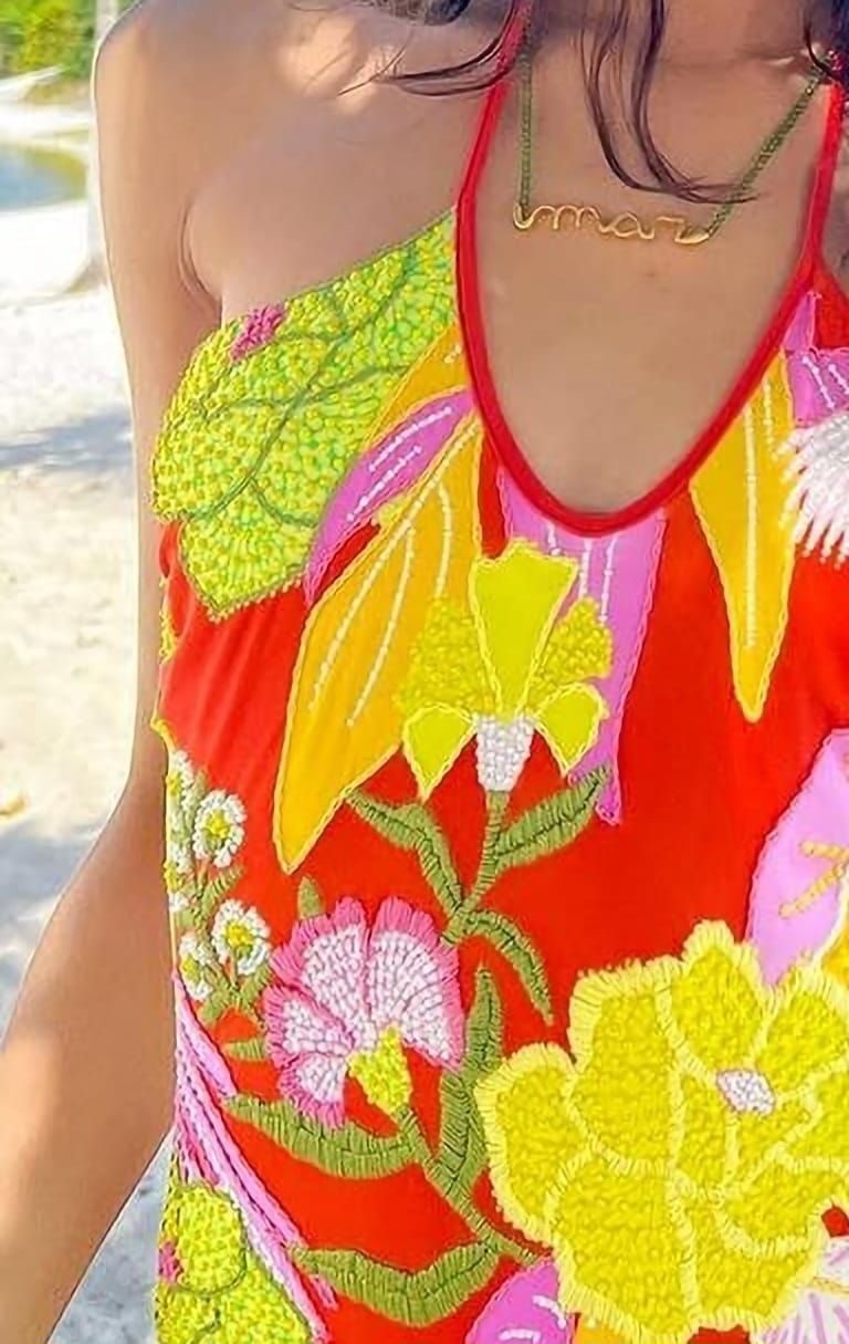 Detalhe de peça com bordado à mão em flores coloridas