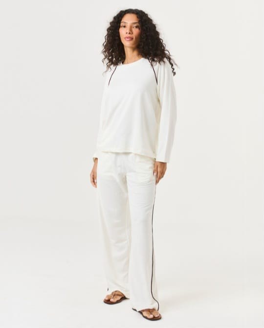 Modelo com conjunto longo off white de blusa raglan e calça com vivo vinho, da Verve